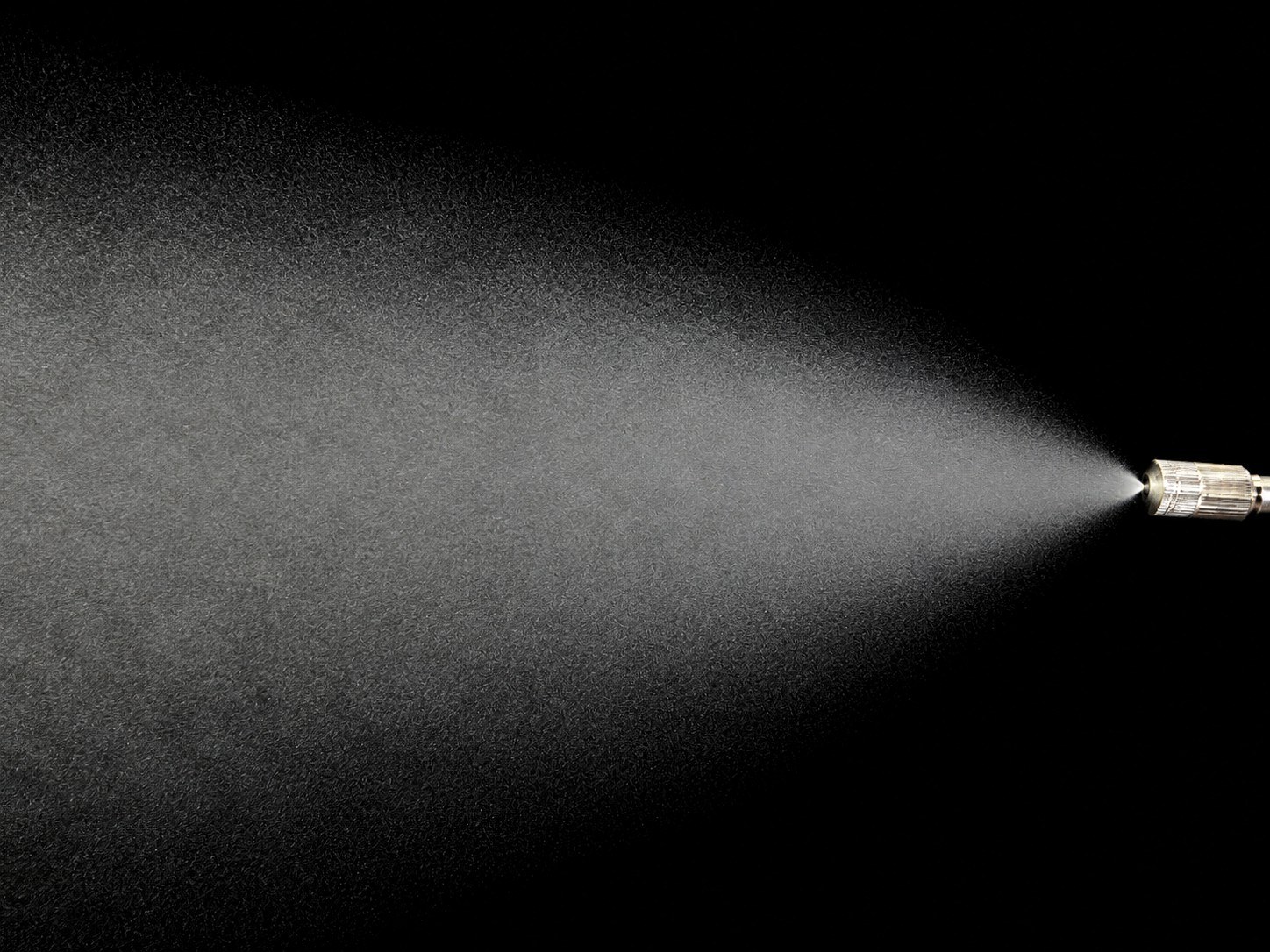 High-pressure precision nozzle creating ultra-fine micron mist plume